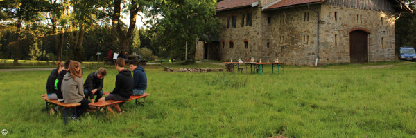 Menschen sitzen im Kreis auf einer Wiese